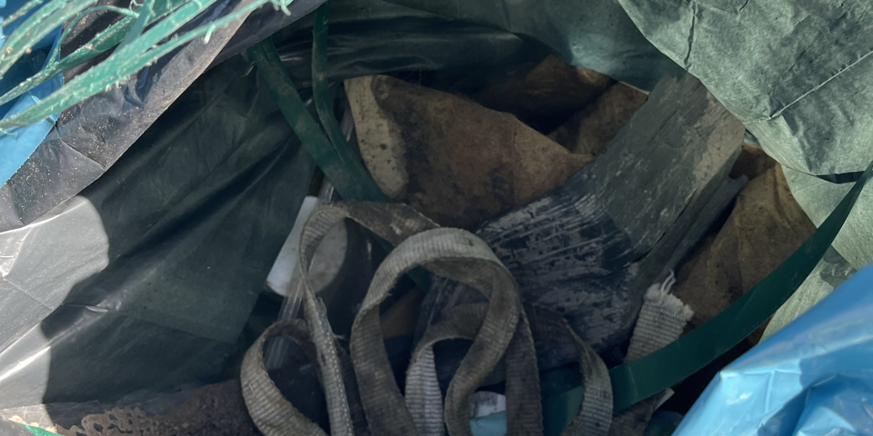 Skräp från naturen i en blå sop-påse