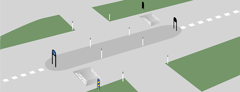 Bilden visar en övergångspassage som säkras upp med hjälp av vägkudde, skyltbågar och pollare