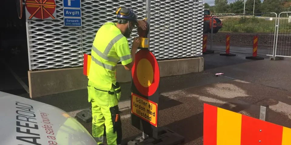 Man justerar till varningslykta på trafikavstängningsmaterial