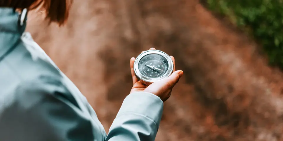 Närbild på en person som håller en kompass i sin hand
