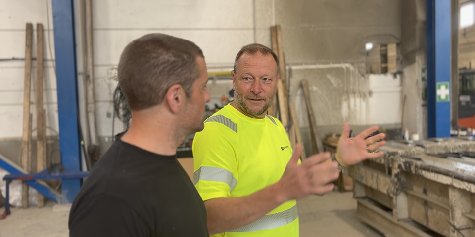 Två manliga medarbetare på ett gjuteri diskuterar