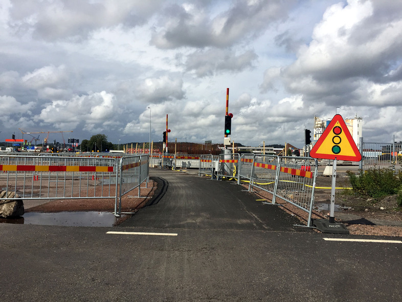 Byggarbetsplats med kravallstaket som skapar en asfalterad promenadväg