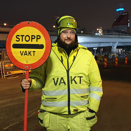 Vägvakten Denny håller stoppsignal längs en väg