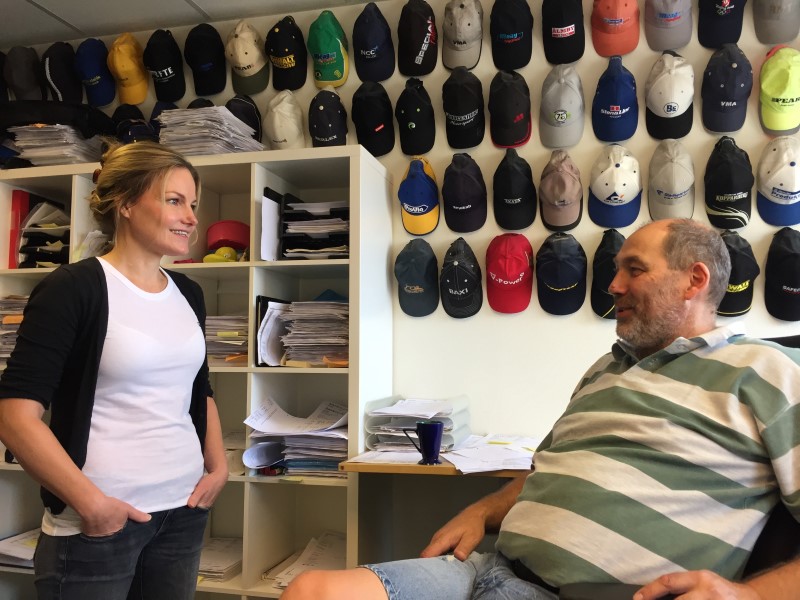 En man och en kvinna framför en vägg med kepsar