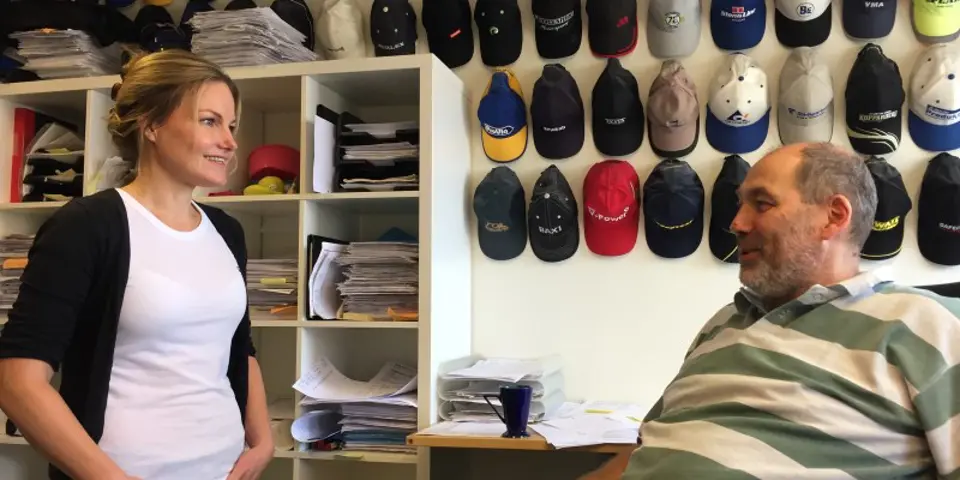 En man och en kvinna framför en vägg med kepsar